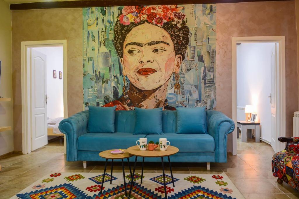 a living room with a blue couch and a painting at White Arrow Apartment in Bajina Bašta