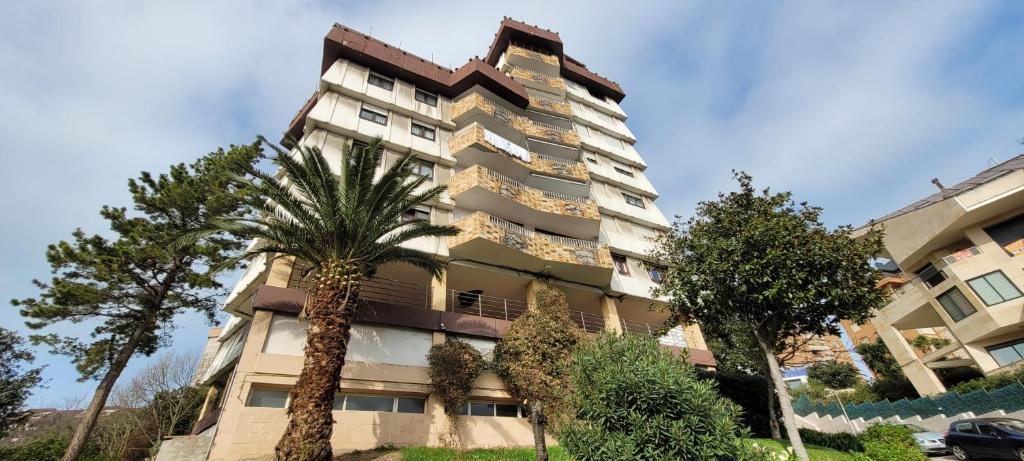 wysoki budynek z palmami przed nim w obiekcie Urbanizacion los Delfines w mieście Santander