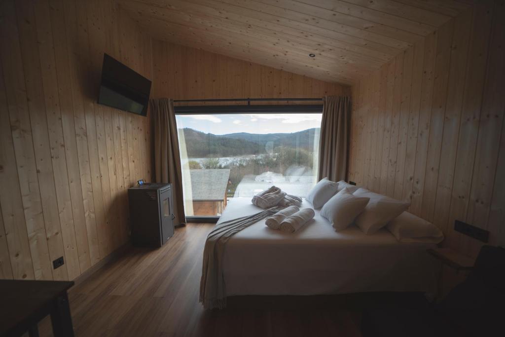 1 dormitorio con 1 cama grande y ventana grande en Cabañas O Recuncho do Sor, en O Barqueiro