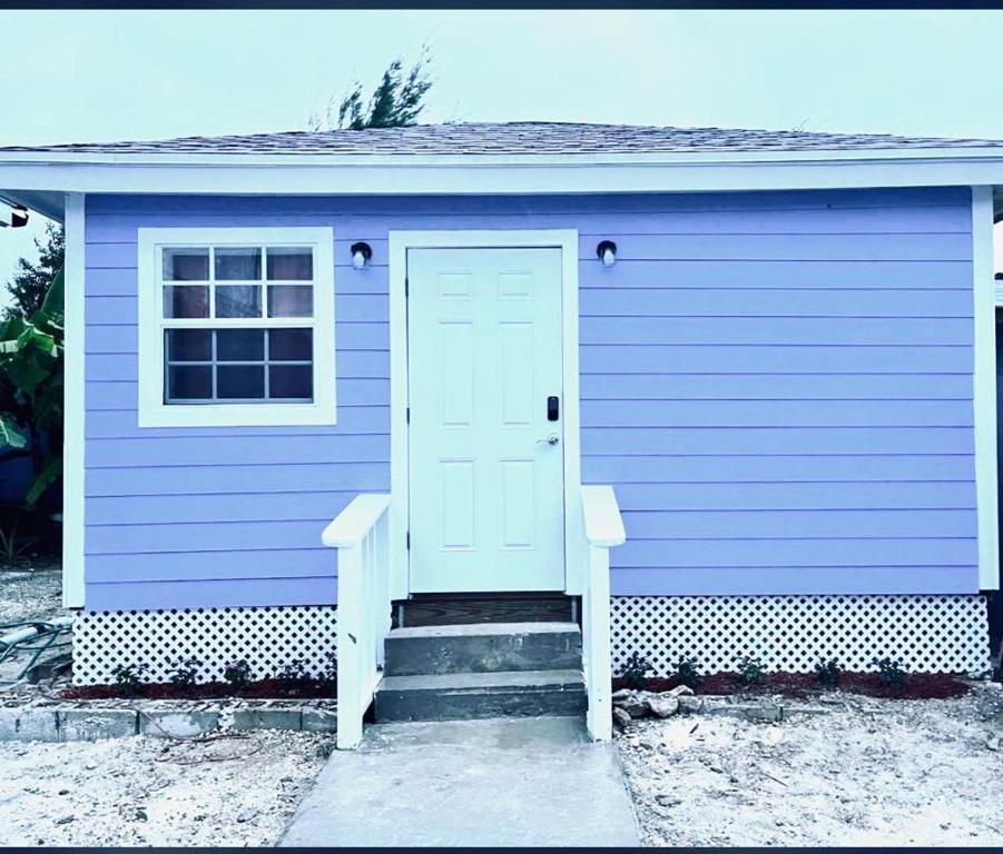 une maison violette avec une porte blanche et des escaliers dans l'établissement SanAndros Airbnb, à Marsh Harbour