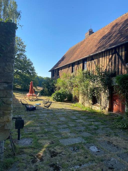 une grange avec deux bancs devant elle dans l'établissement Manoir de la Jaunière maison de charme Pays d’Auge, à Neuville-sur-Touques