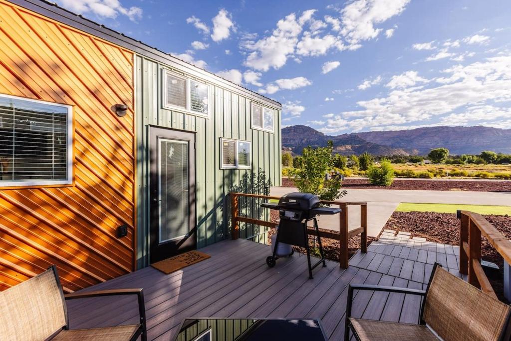 a deck with chairs and a table on a house at The Narrows Tiny Home in Apple Valley