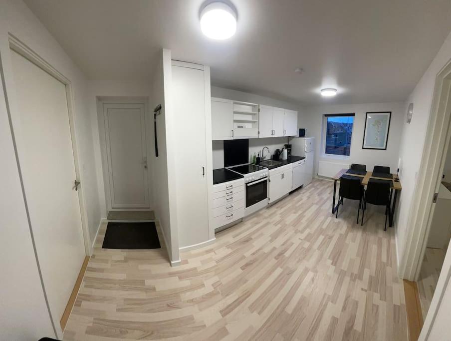 a kitchen with white cabinets and a wooden floor at Apartment in Tórshavn. in Tórshavn
