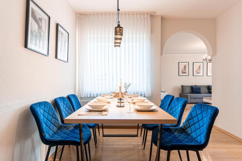 a dining room with a table and blue chairs at lionApartments Leverkusen #2 in Leverkusen
