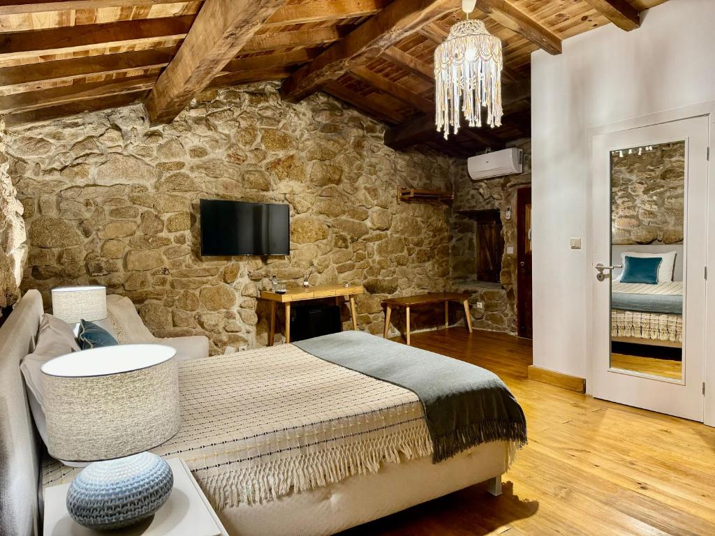 um quarto com uma cama grande numa parede de pedra em Quinta do Nobre em Marialva