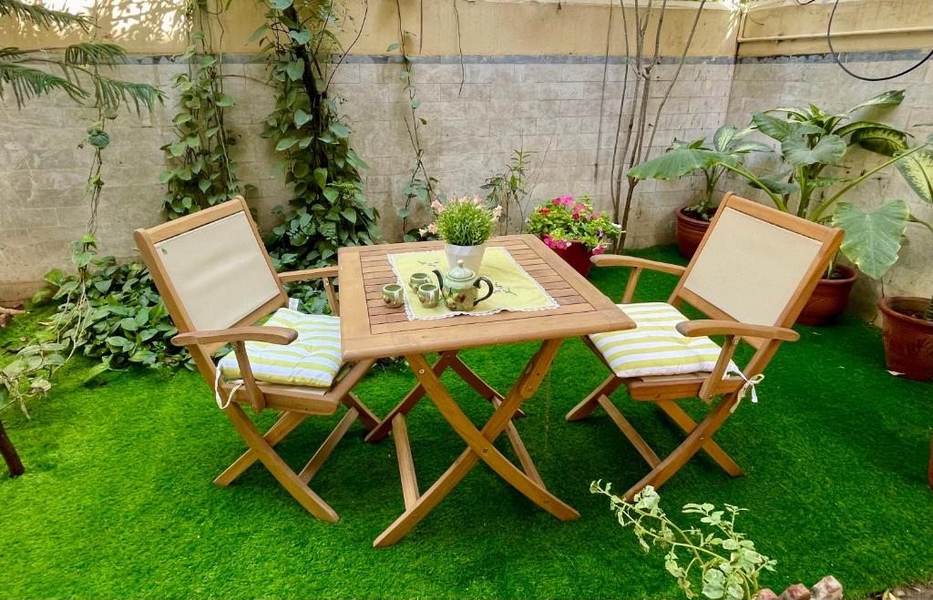 2 chaises et une table en bois avec une table et une table dans l'établissement Mohalla Rooftop Retreat, à Karachi