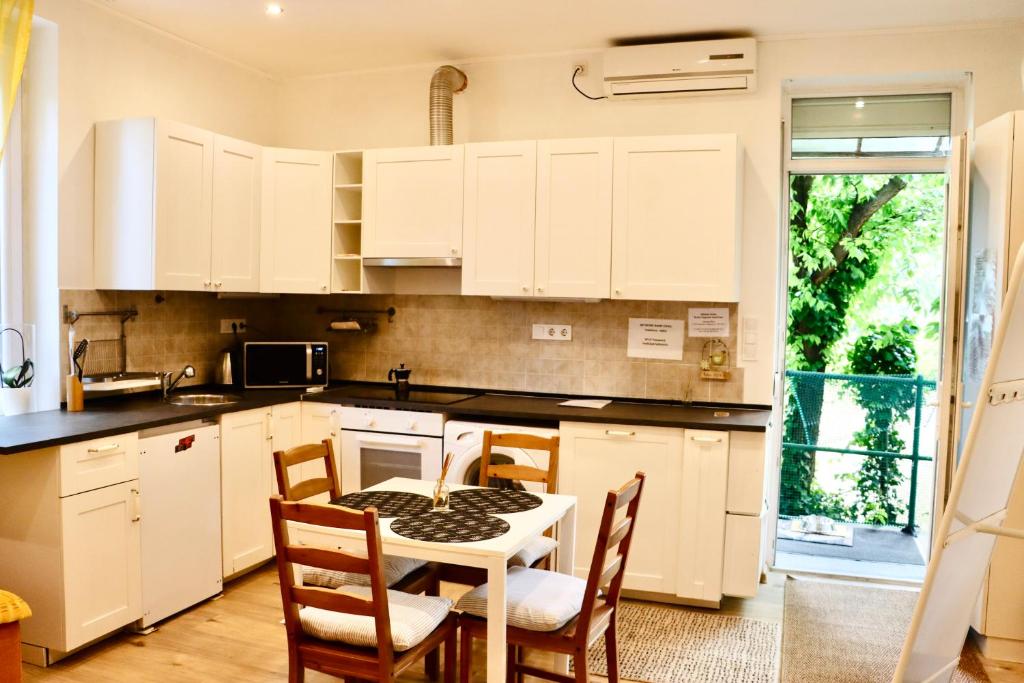 ブダペストにあるCozy Hillside Home in Budapest with Patioの白いキャビネット、テーブルと椅子付きのキッチンが備わります。