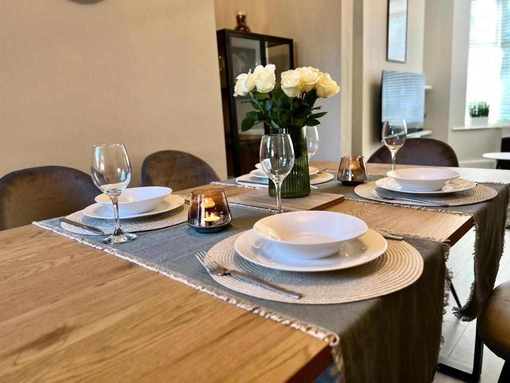 una mesa con platos y vasos y un jarrón de flores en The Stunning house welcomes you en Liverpool