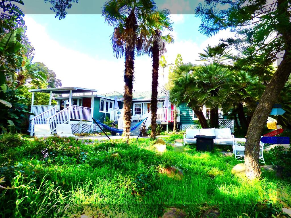 a yard with palm trees and a house with a swing at Bohemian Art & Garden Cottage Santa Barbara in Santa Barbara