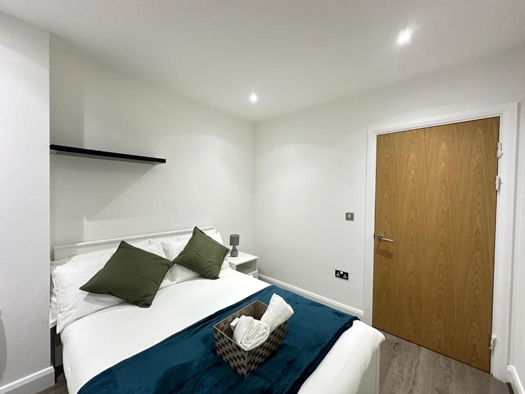 a bedroom with a white bed with a wooden door at Luxury 2 Bedroom Penthouse Near Central London in London