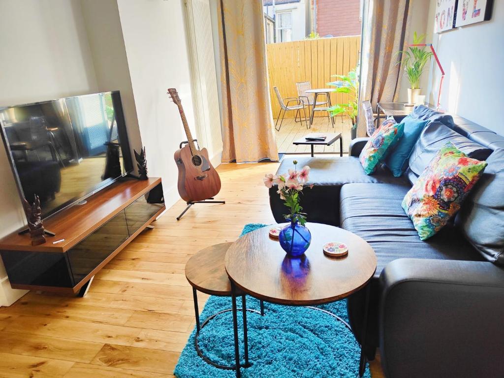 a living room with a couch and a tv and a table at Modern Central Brighton patio flat - free parking! in Brighton & Hove