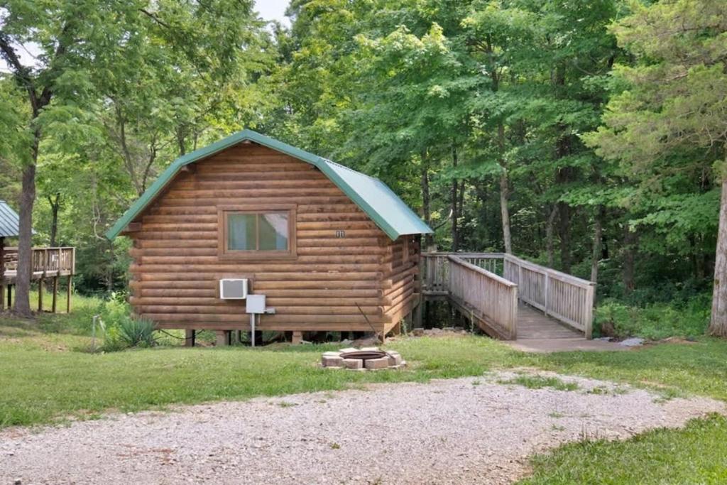 a log cabin with a green roof and a porch at Rustic Cabin with Pool Access in Bloomington