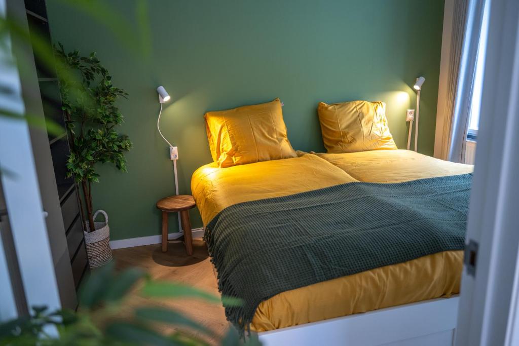 1 dormitorio con 1 cama con sábanas amarillas y lámpara en Kahakai Beach House - Unique Outdoor Kitchen - next to local lake and 15 min. the from beach en Noordwijkerhout