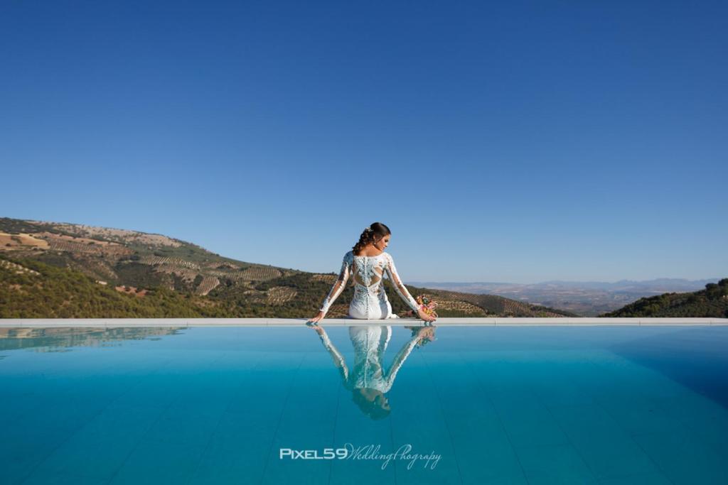 Una mujer con un vestido blanco parada en el agua en CASA RURAL LA CHOZA DE MINDO, en Granada