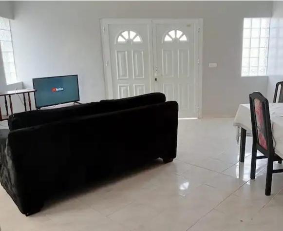 a black couch in a living room with a laptop at Casa dos Amigos in Calheta de São Miguel