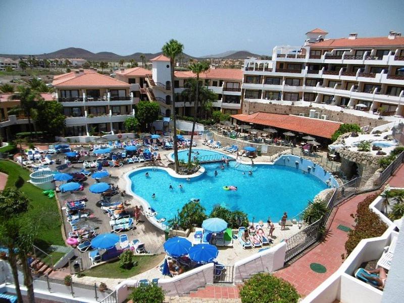 een groot zwembad met blauwe parasols en een hotel bij GOLF DEL SUR ALBATROS 5 bed places apartment in San Miguel de Abona
