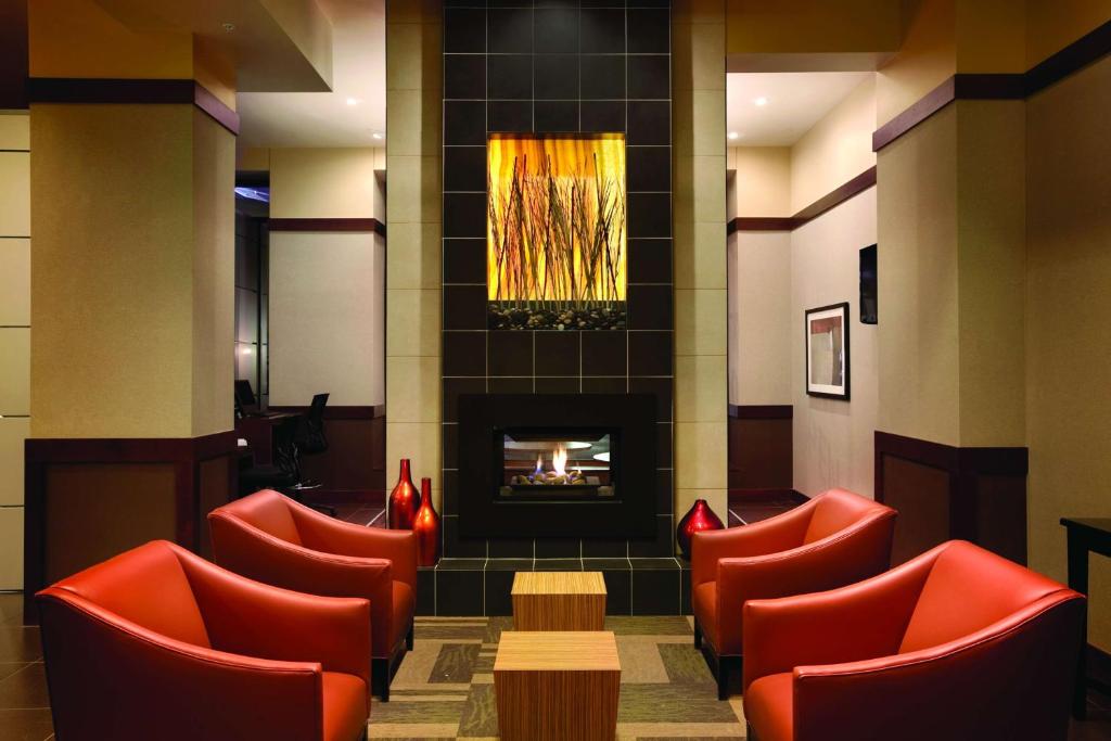 a waiting room with red chairs and a fireplace at Hyatt Place Des Moines Downtown in Des Moines