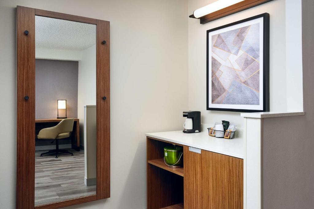 a hotel room with a mirror and a desk at Hyatt Place Greensboro in Greensboro