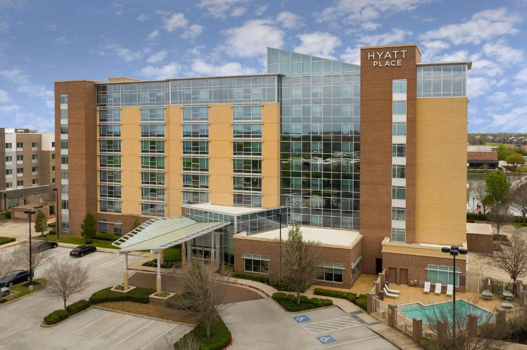 un grand immeuble de bureaux avec un panneau sur celui-ci dans l'établissement Hyatt Place Sugar Land, à Sugar Land