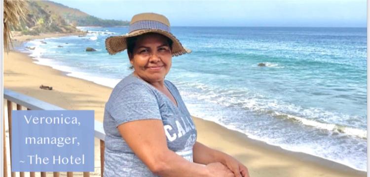 a woman wearing a hat sitting on the beach at asante sana - Playa Marshell in Chimo