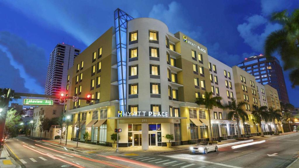 un edificio alto con un cartel en una calle de la ciudad en Hyatt Place West Palm Beach en West Palm Beach