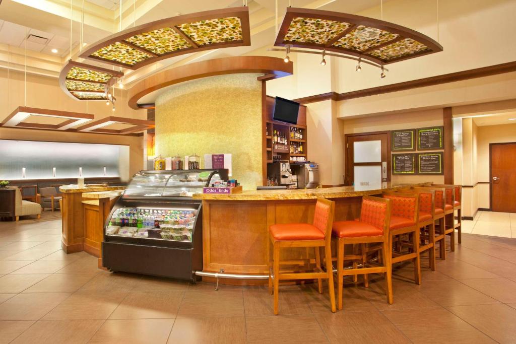 un restaurante con un bar con sillas naranjas y una barra en Hyatt Place Orlando Airport en Orlando