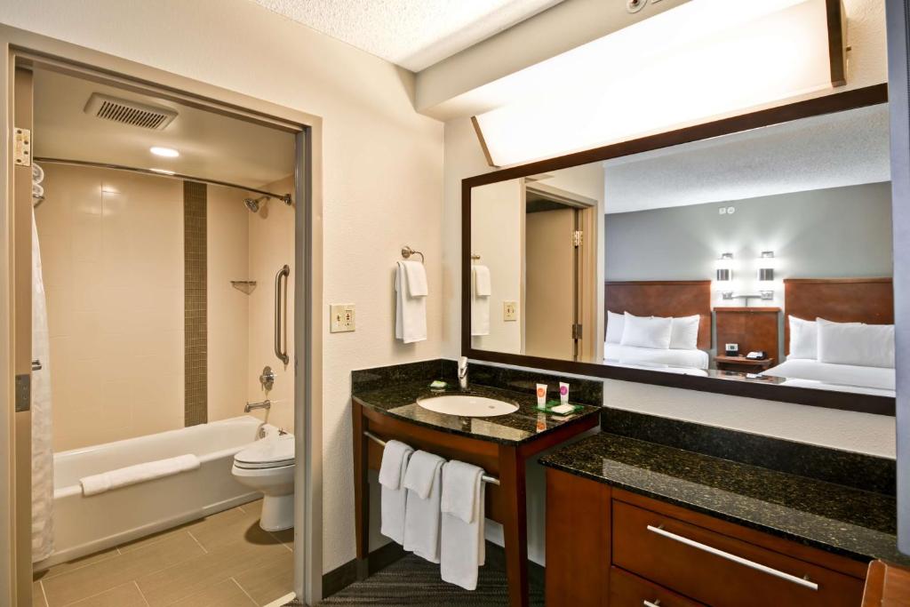 a bathroom with a sink and a toilet and a mirror at Hyatt Place Reno/Tahoe Airport in Reno