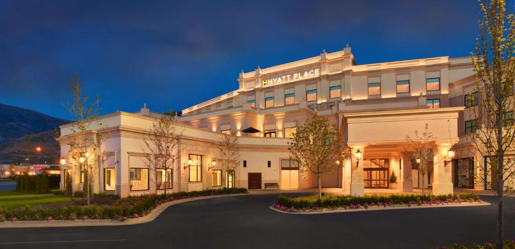 a large white building with a driveway in front of it at Hyatt Place Salt Lake City Farmington Station Park in Farmington