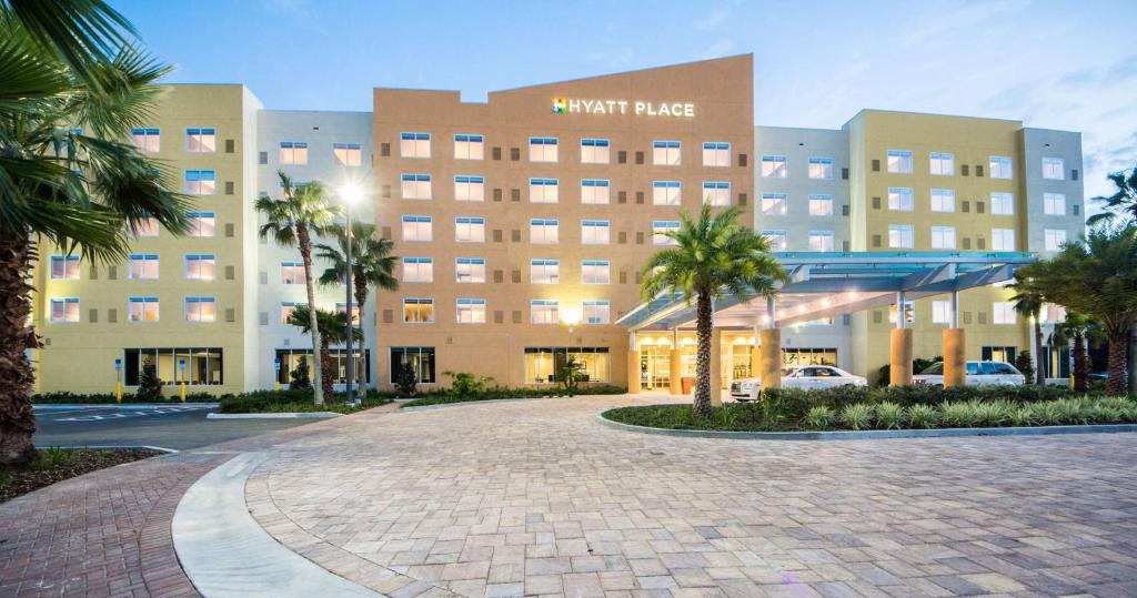 a large hotel with palm trees in front of it at Hyatt Place Orlando/Lake Buena Vista in Orlando