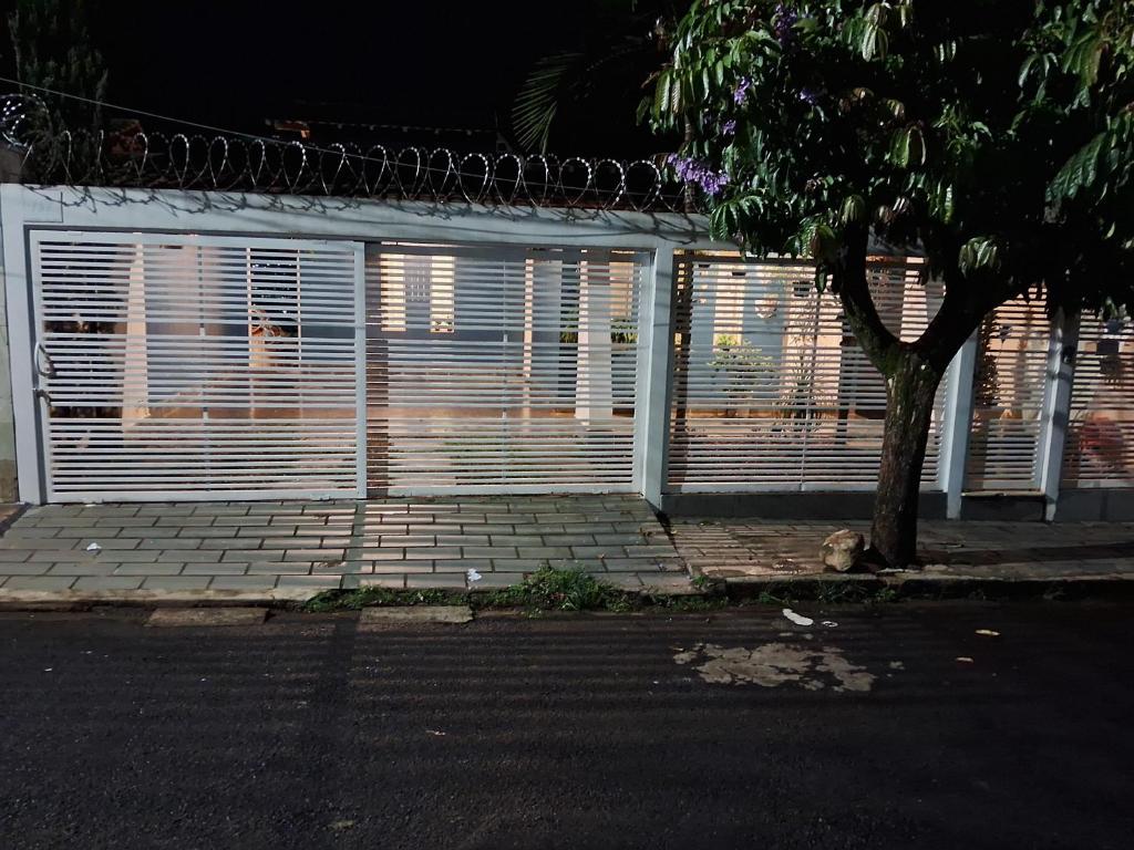 un garage blanc avec des fenêtres à volets et un arbre dans l'établissement Aconchego, à Araxá