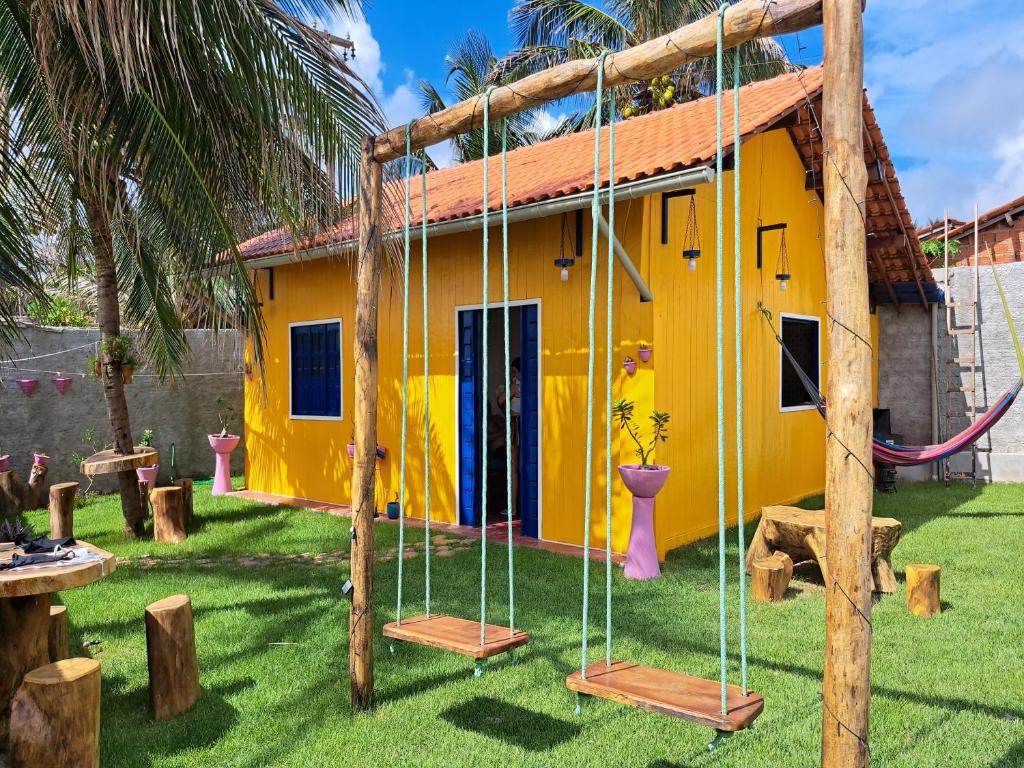 une maison jaune avec des balançoires devant elle dans l'établissement Casa de Praia Tutóia, à Tutóia