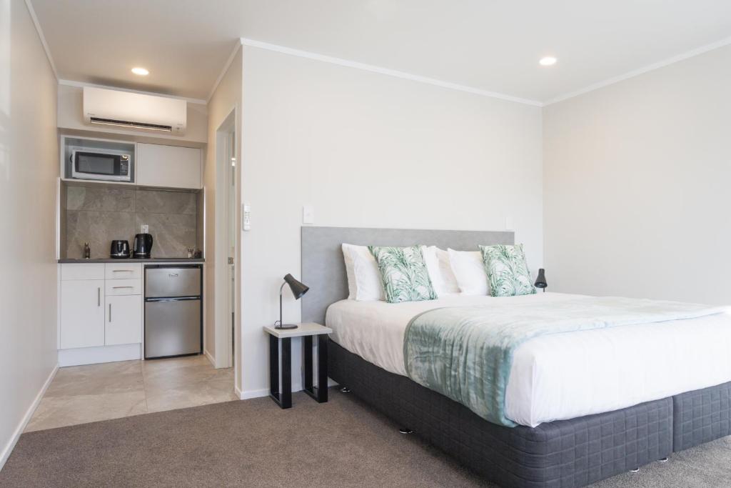 a bedroom with a large bed and a kitchen at BK's Pohutukawa Lodge in Whangarei