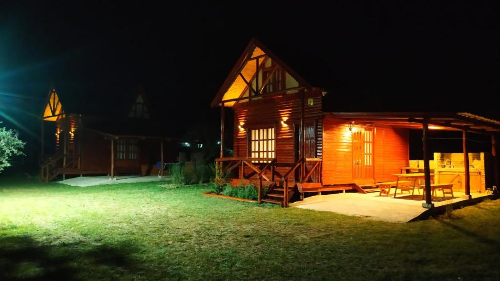 een houten hut met een tafel in de tuin 's nachts bij Cabañas en los reartes in Los Reartes