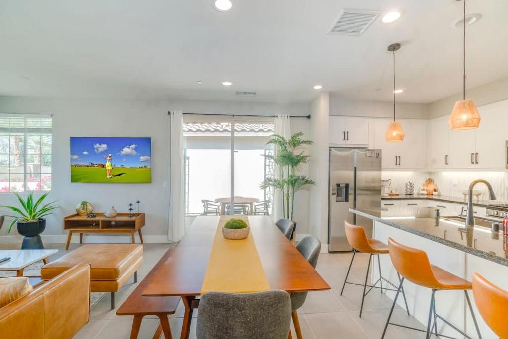 uma cozinha e sala de estar com uma mesa de madeira e cadeiras em Desert Bliss by VARE Putting Green Pool Spa em La Quinta