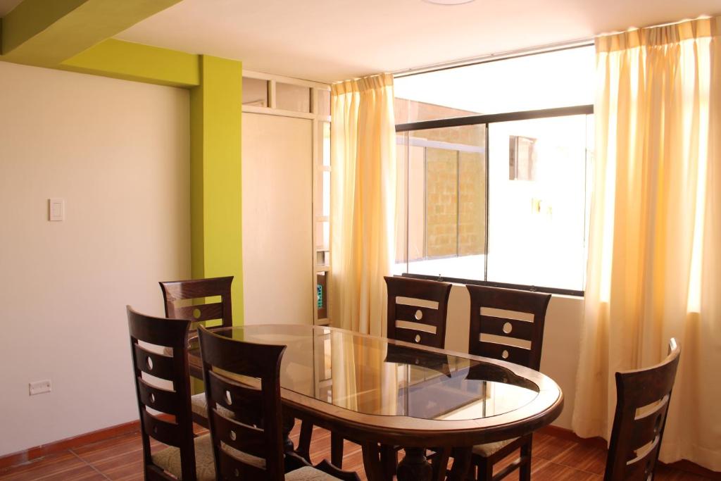uma sala de jantar com uma mesa de vidro e cadeiras em 2 de Mayo Apartamento 2do piso em Tacna