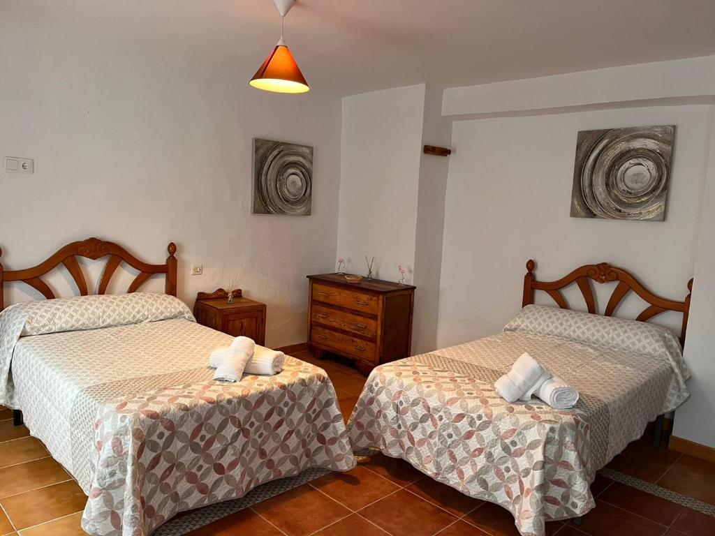 a bedroom with two beds and a dresser in it at Casa Los Belenes in Cazorla