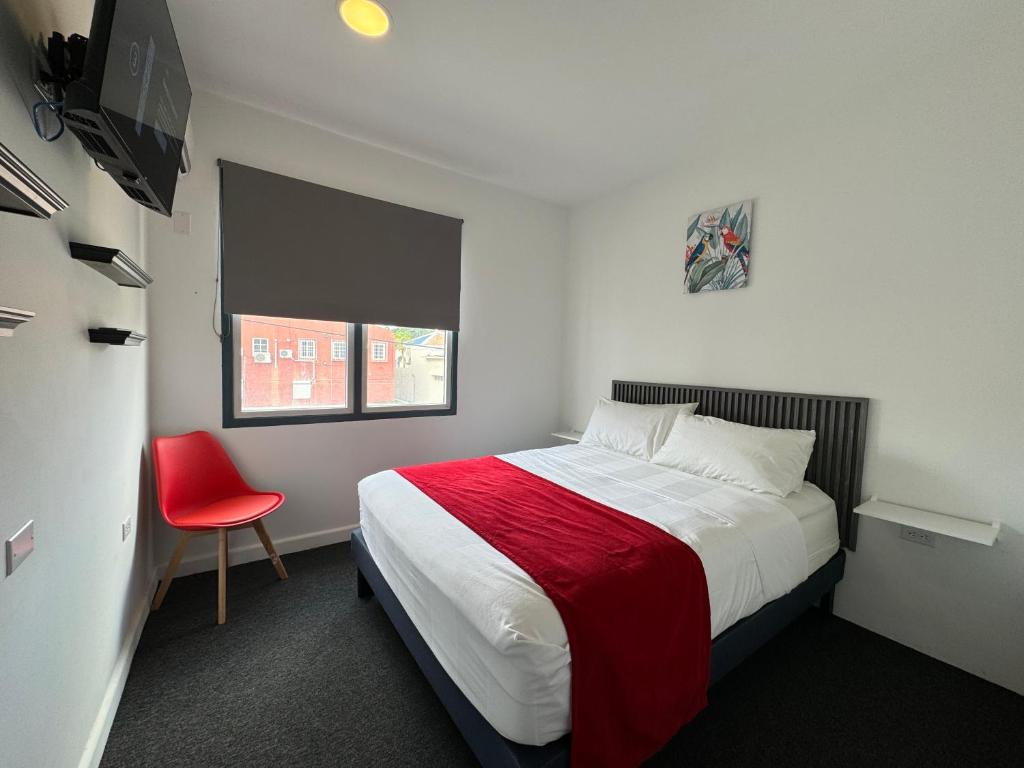 1 dormitorio pequeño con 1 cama y 1 silla roja en Central Boutique Hotel en Oranjestad