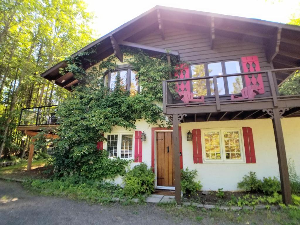 een klein huis met een balkon en rode accenten bij Chalet in the Laurentian Mountains in Sainte-Agathe-des-Monts