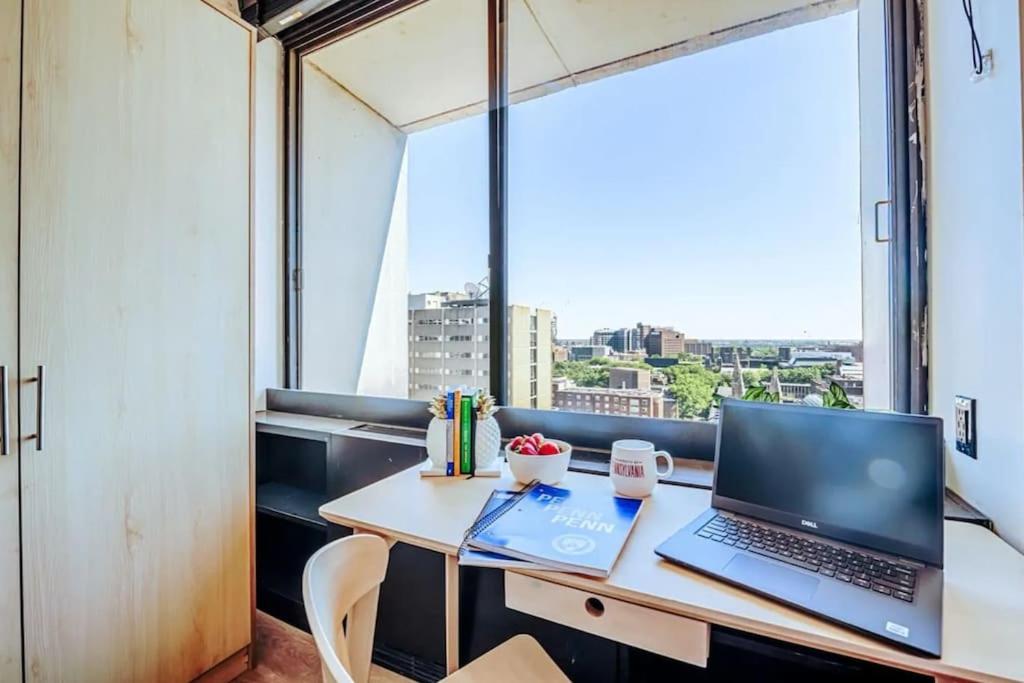 a laptop computer sitting on a desk in a room with a window at City Chic Retreat: The Chestnut Serenity in Philadelphia