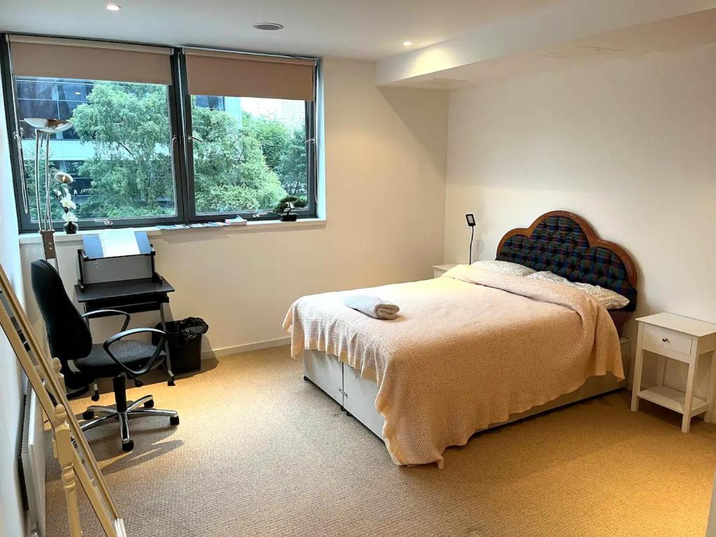 um quarto com uma cama, uma secretária e uma janela em Spacious Queen Bed City Centre Penthouse With Balcony - Homeshare - Live In Host em Glasgow