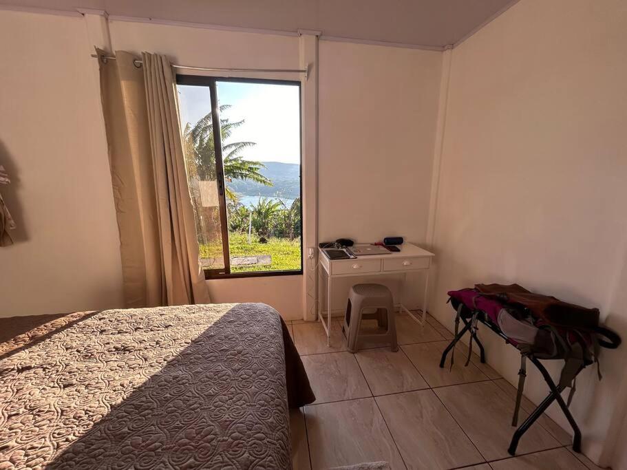 1 dormitorio con cama, escritorio y ventana en LakeLifeCR Tu casa frente al Lago Arenal, en Tilarán