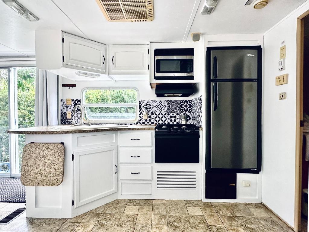 a kitchen with white cabinets and a black refrigerator at Descanso, tranquilidad y desconexión a un paso de todo. in Miami