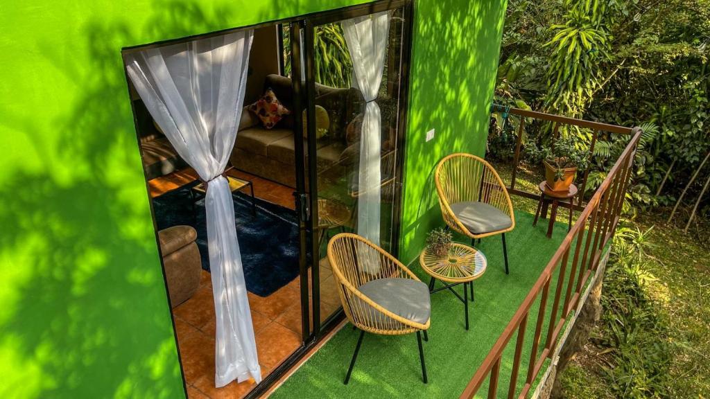 a green house with two chairs and a couch at Casa Euphonia Monteverde in Monteverde Costa Rica