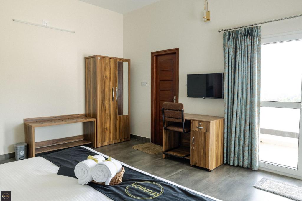 a hotel room with a bed and a television at Reunion Solandis - Service Apartments in Udupi