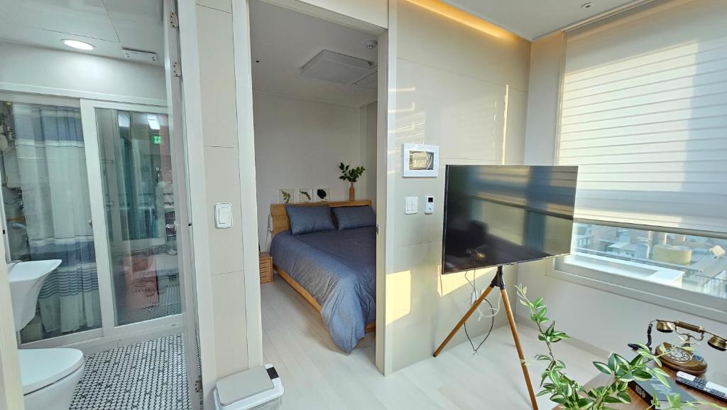 首爾的住宿－Gamseong house #Gimpo airport 10 min #Hwagok station #Netflix #Beamprojet #niceview，一间卧室配有一张床,并在一间客房内配有电视。