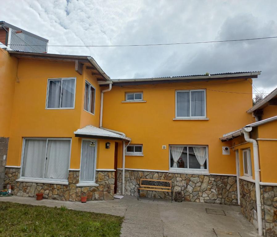 una casa amarilla con una pared de piedra en La Escondida en Ushuaia