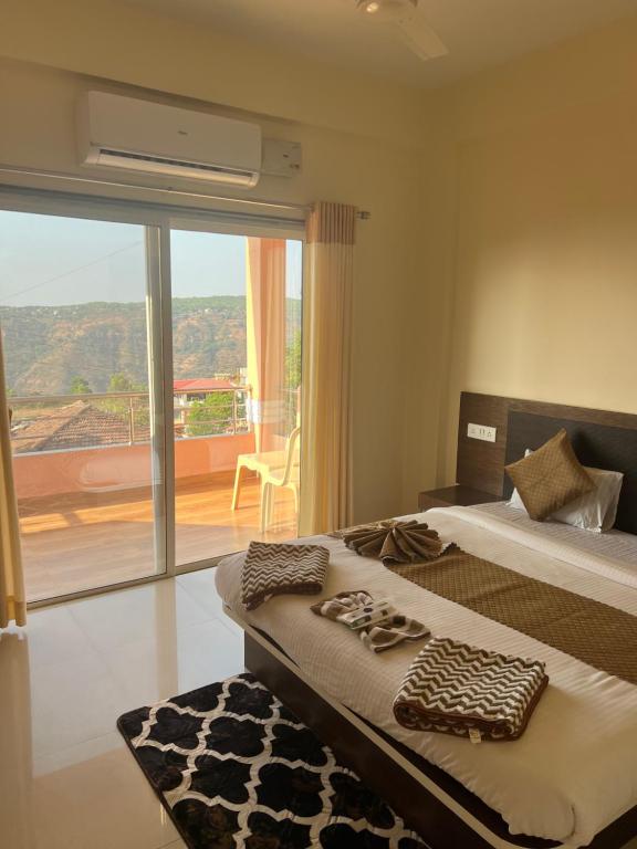 a bedroom with two beds and a large window at Hotel Mahabaleshwar Mount View in Mahabaleshwar