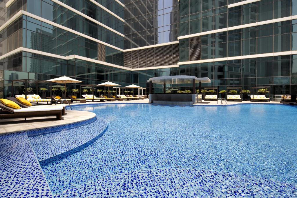 uma grande piscina com cadeiras e um edifício em Taj Dubai no Dubai