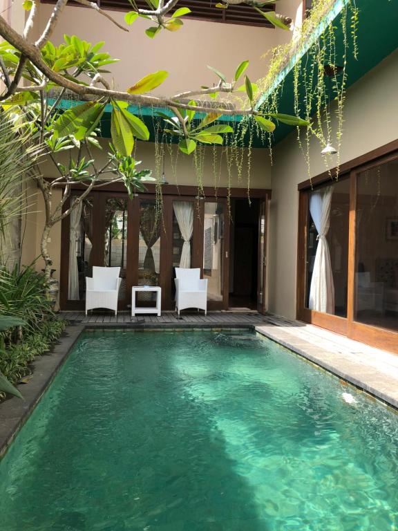 a swimming pool in a villa with two chairs at Nuansa Kori House 4 Bedrooms, Jimbaran in Jimbaran