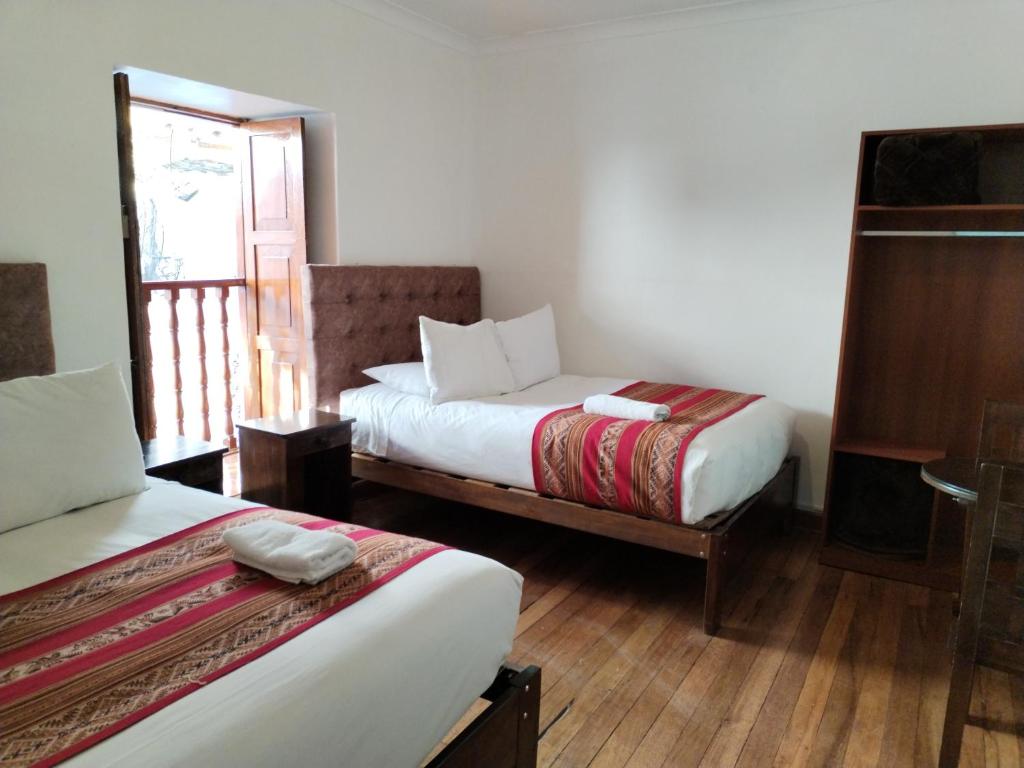 a hotel room with two beds and a window at Paqarina San Blas in Cusco